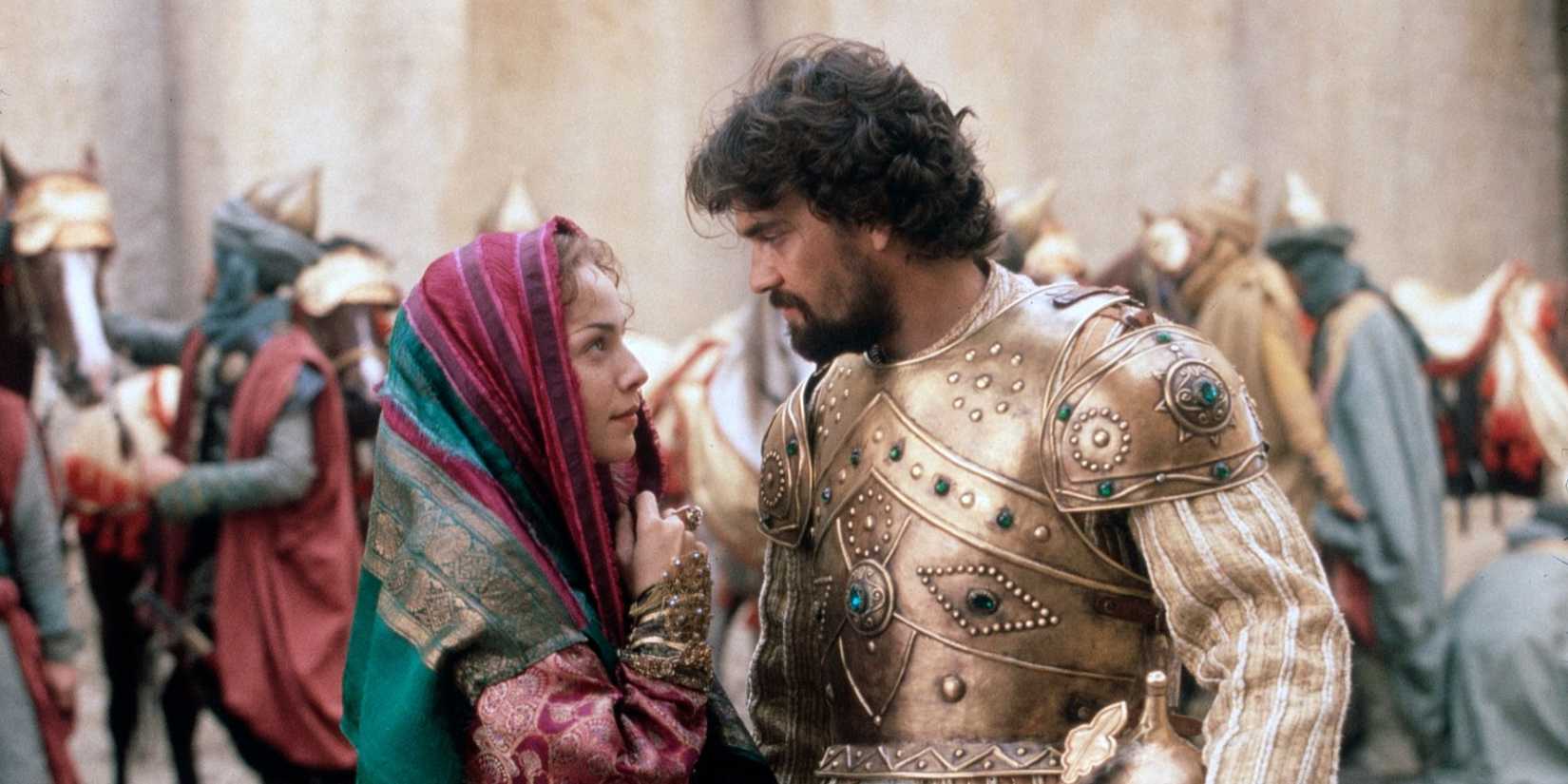 Mili Avital looks at Dougray Scott wearing armor in the Arabian Nights miniseries