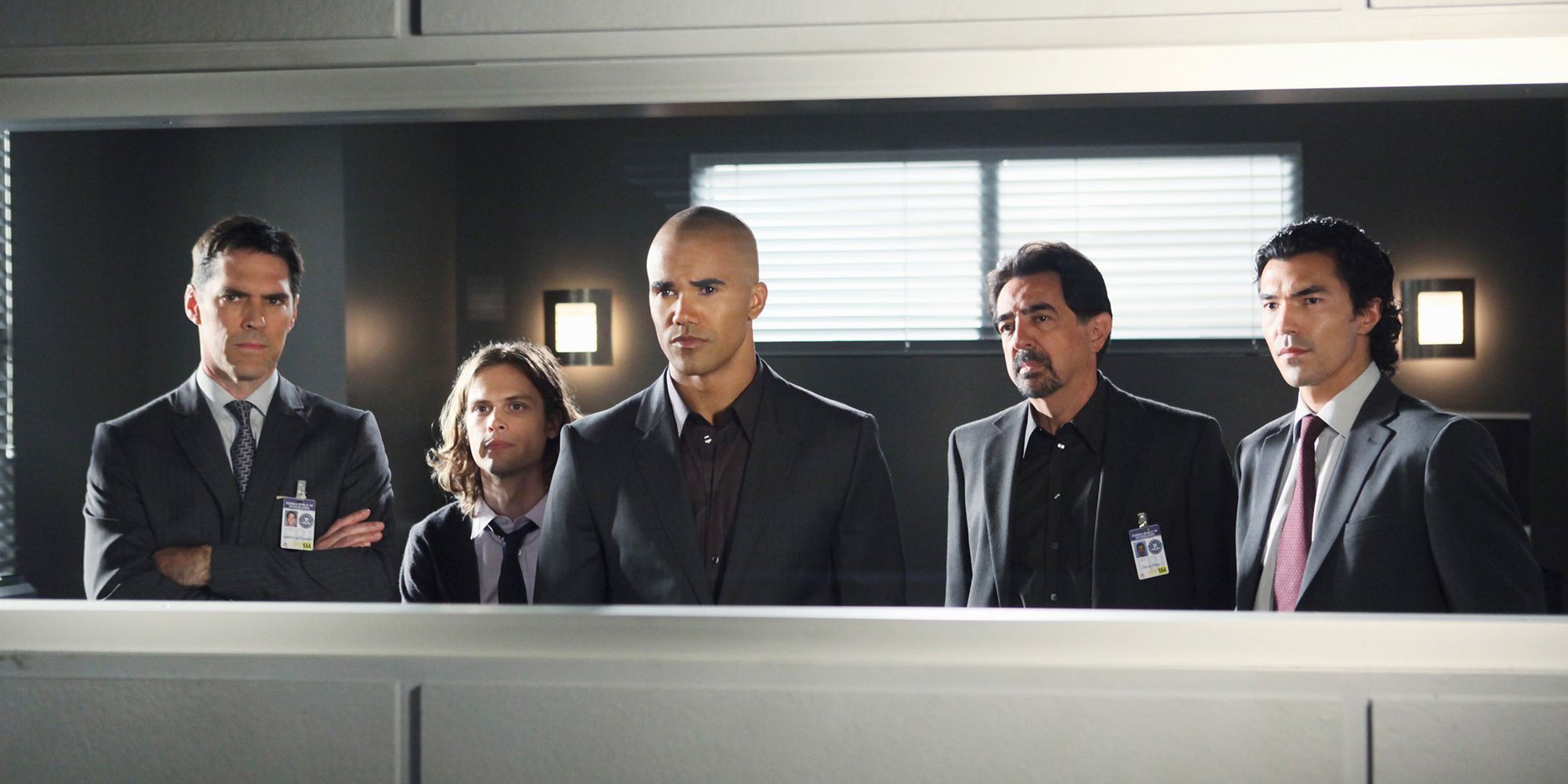 Thomas Gibson, Matthew Gray Gubler, Shemar Moore, Joe Montagna, Ian Anthony Dale looking at an interrogation mirrored glass in Criminal Minds