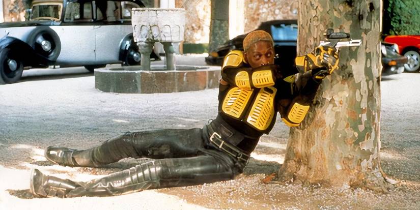 Simon laying on the ground and aiming a gun in Simon Sez
