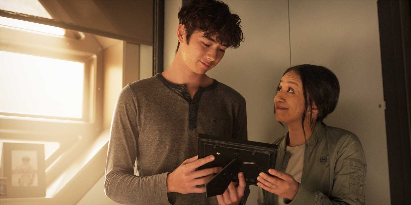 Alex and Kelly Baldwin looking at a framed photo and smiling.