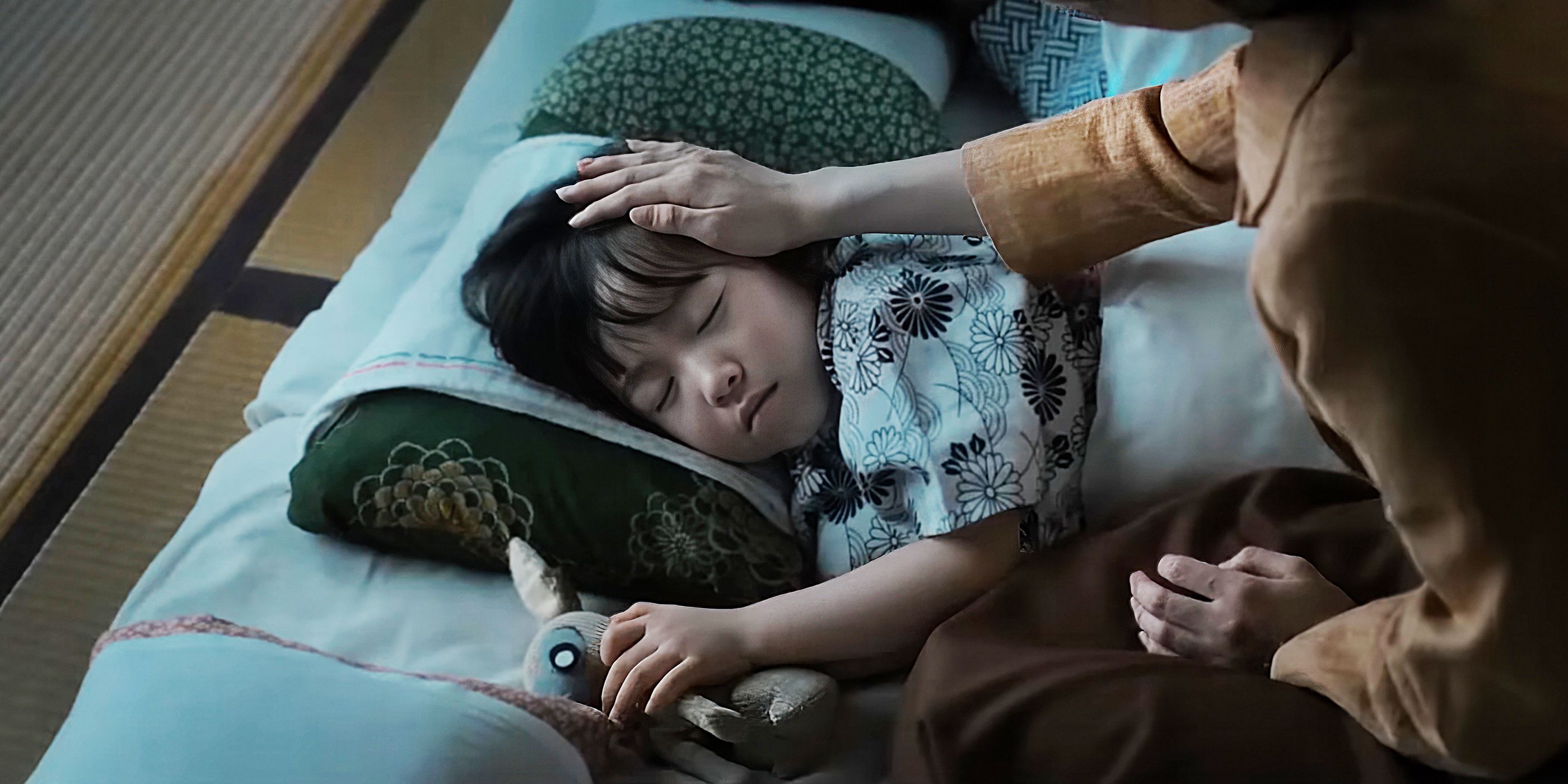 A woman brushes a sleeping little girl's hair back.