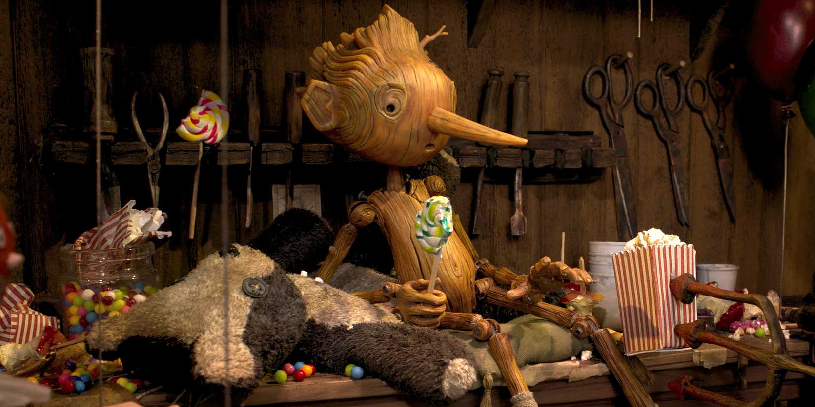 Pinocchio sitting around a bunch of candy and treats in 'Guillermo del Toro's Pinocchio'