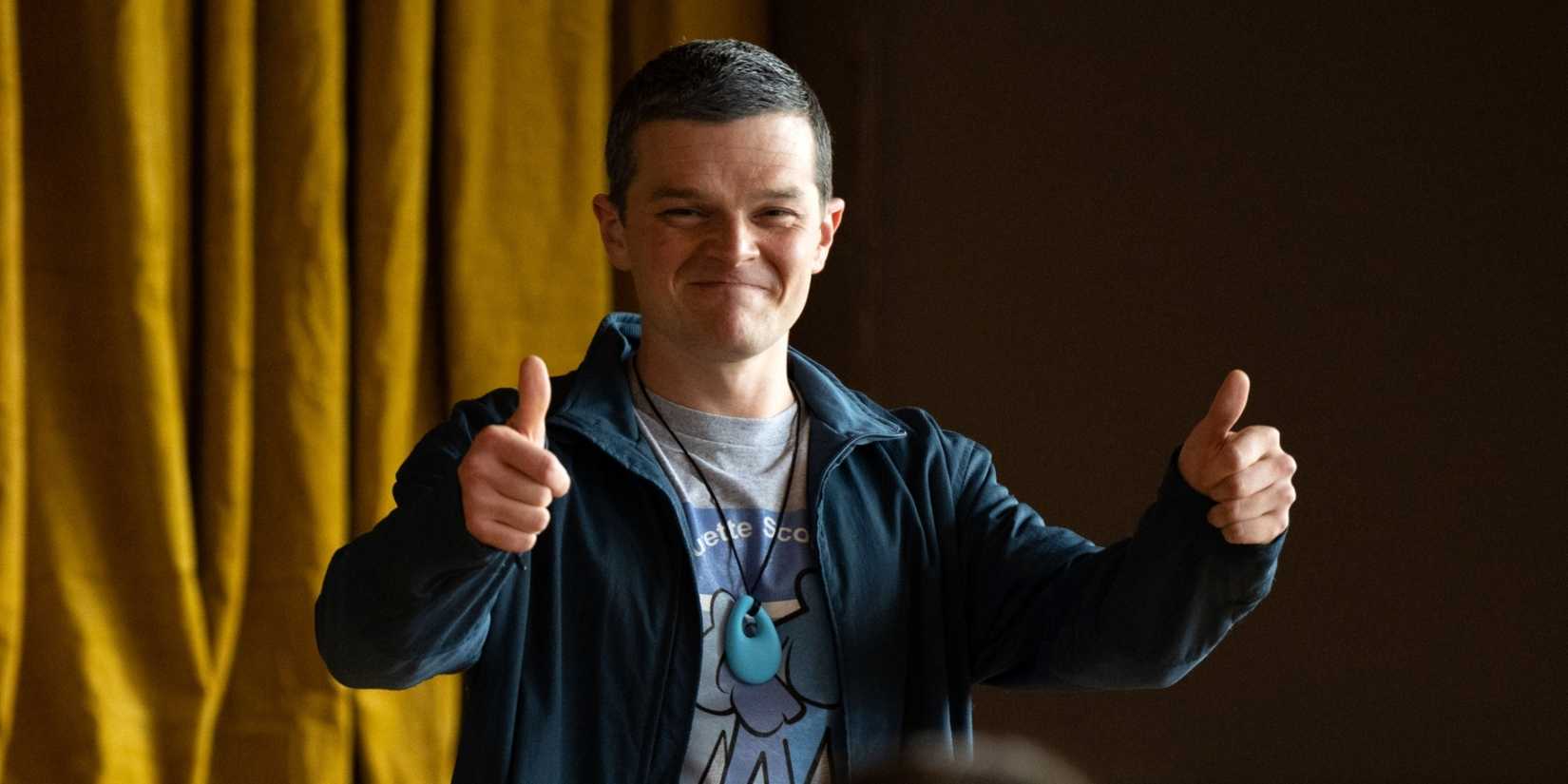 Robert Aramayo as John Davidson giving two thumbs up with a slight smile in I Swear