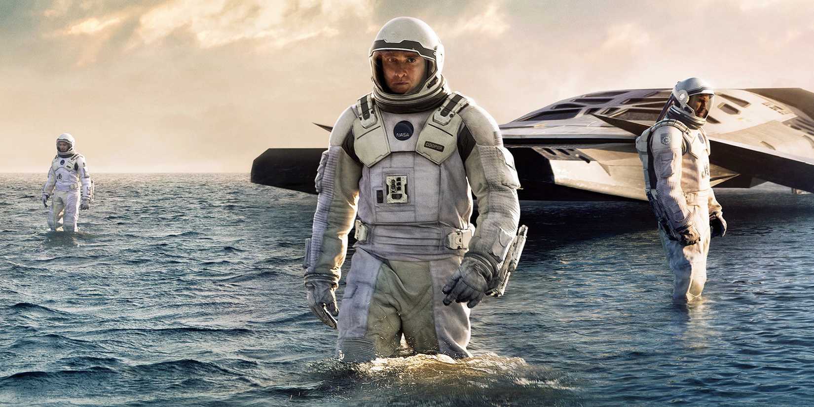 Interstellar - 2014  - three astronauts standing in an ocean, with the space ship behind them