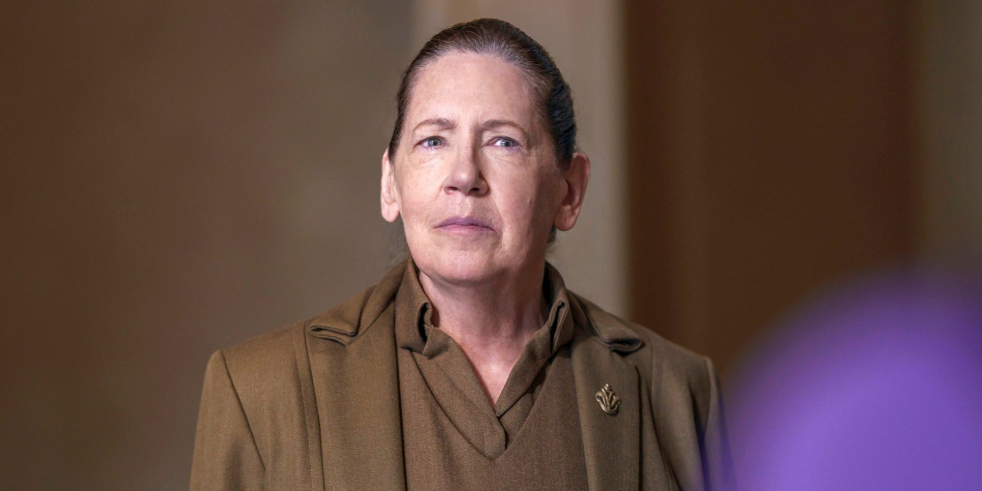 Ann Dowd as Aunt Lydia looking forward with a serious expression in The Testaments