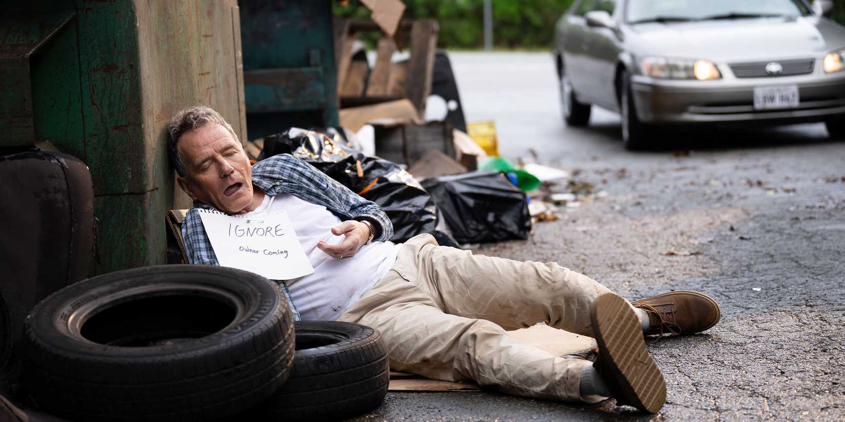Hal lying agains a dumpster in an alley, passed out, with a sign on his chest that says IGNORE.