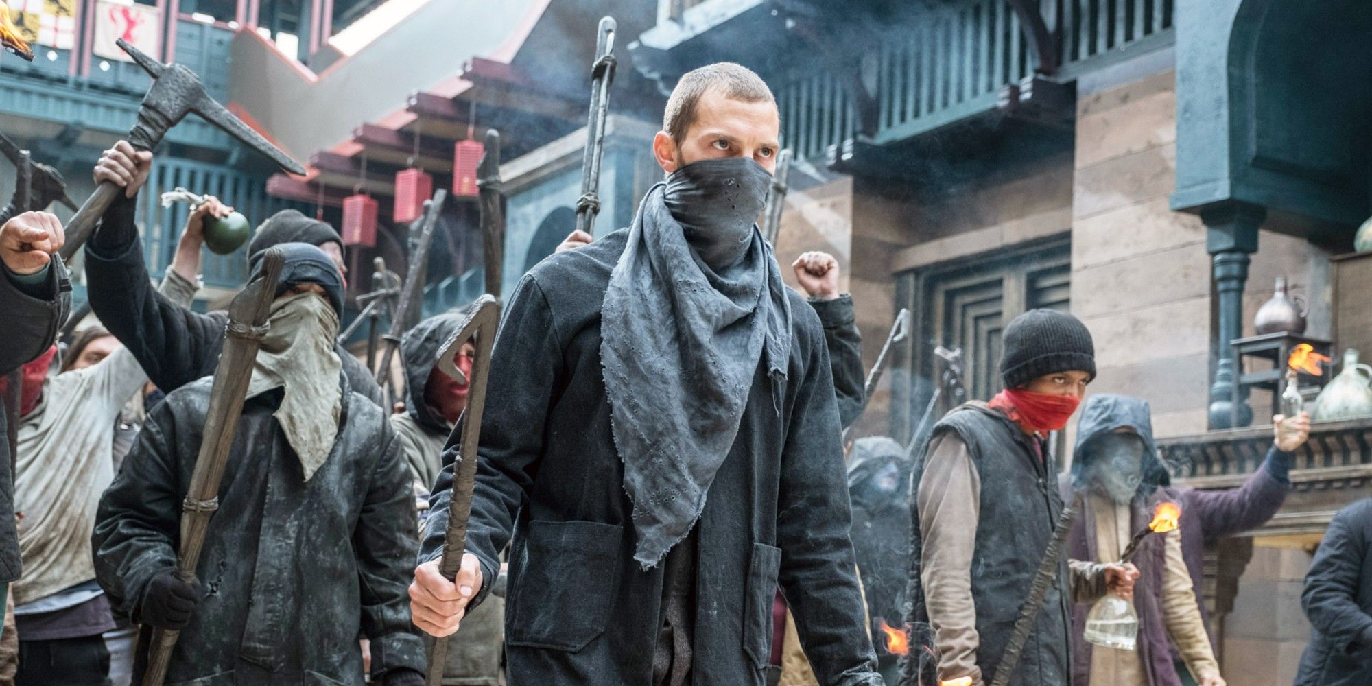 Jamie Dornan leading a mob, with bandanas covering their faces, through town in Robin Hood 2018
