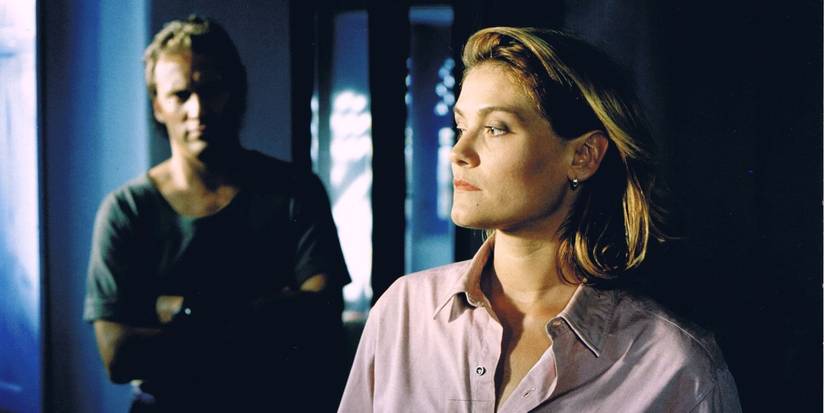 A woman looking to the side while a man standing behind her in Under Suspicion