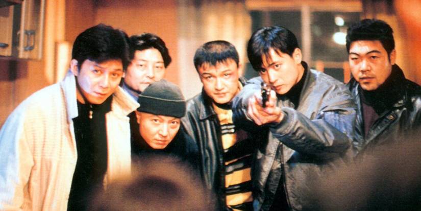 Park Joong-hoon pointing a gun while surrounded by men looking at someone off screen in Nowhere to Hide