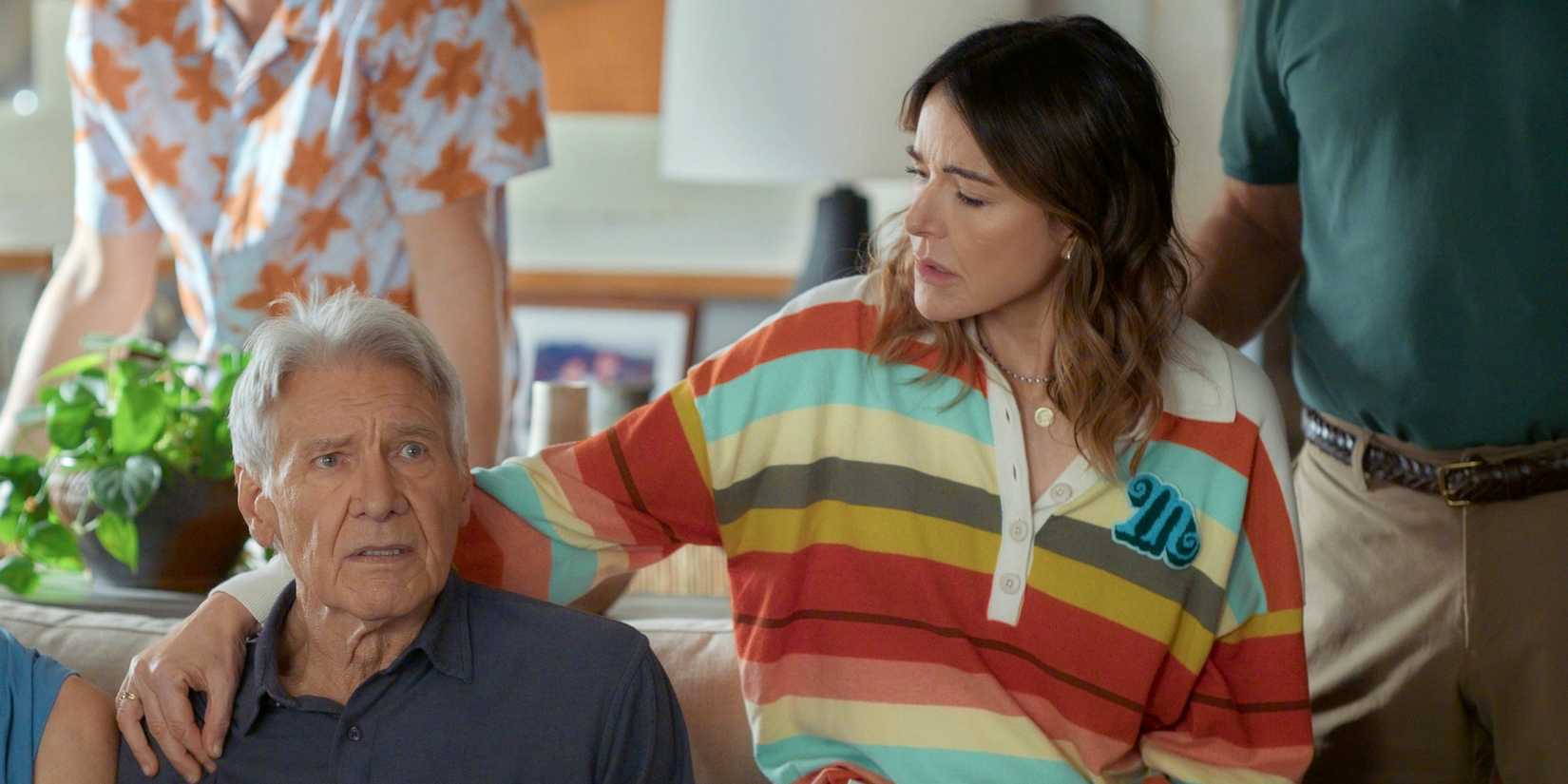 Christa Miller as Liz sitting on the couch with her arm around Harrison Ford as Paul in Shrinking Season 3