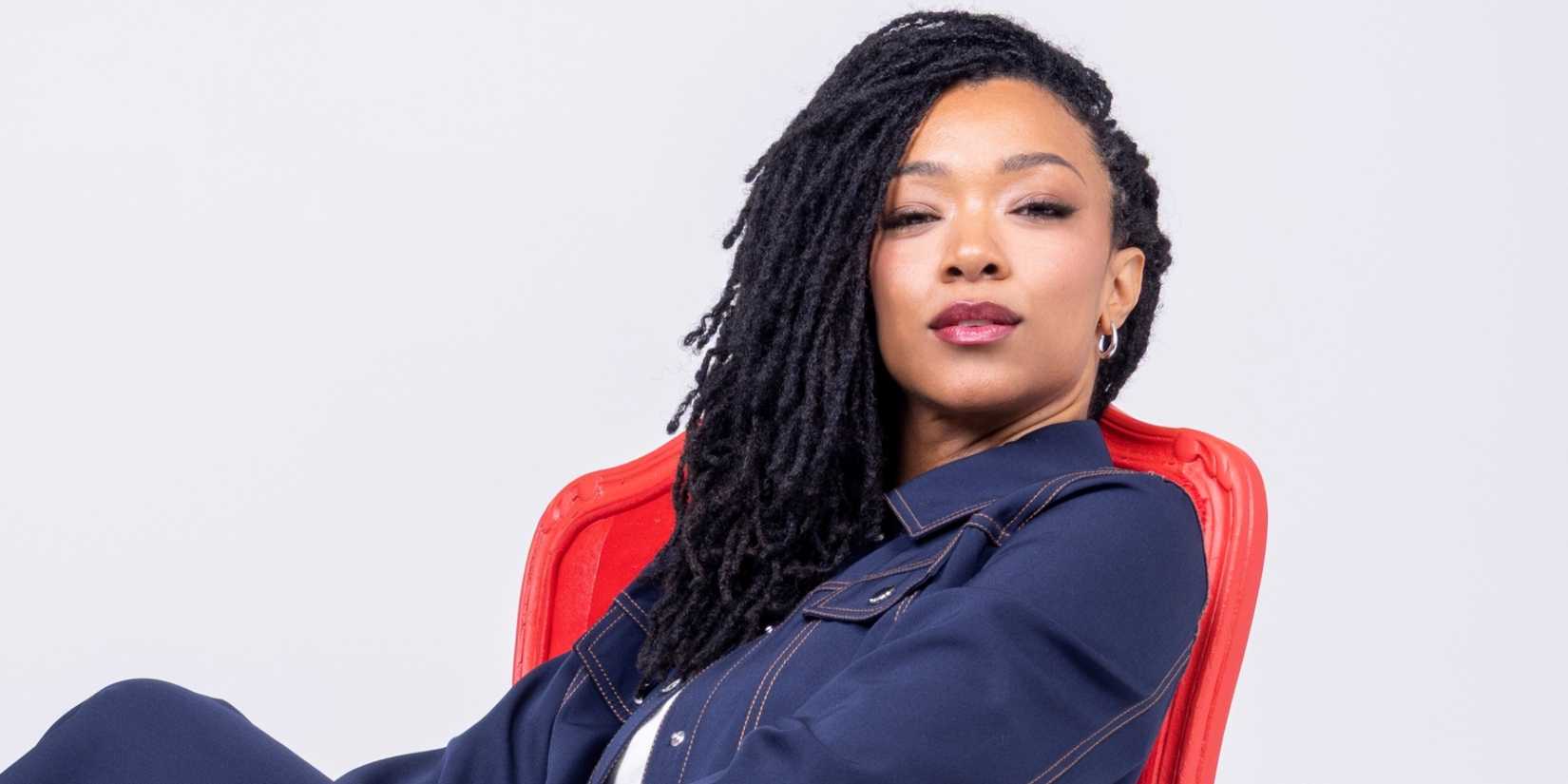 Sonequa Martin-Green sitting in a red chair with her hair down in a promo photo from her PR