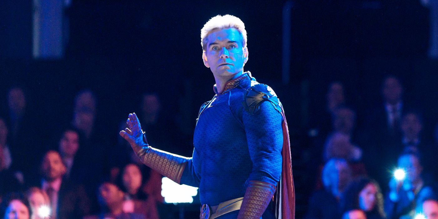 Homelander holds his hand up to quiet a crowd, looking behind him in irritation.