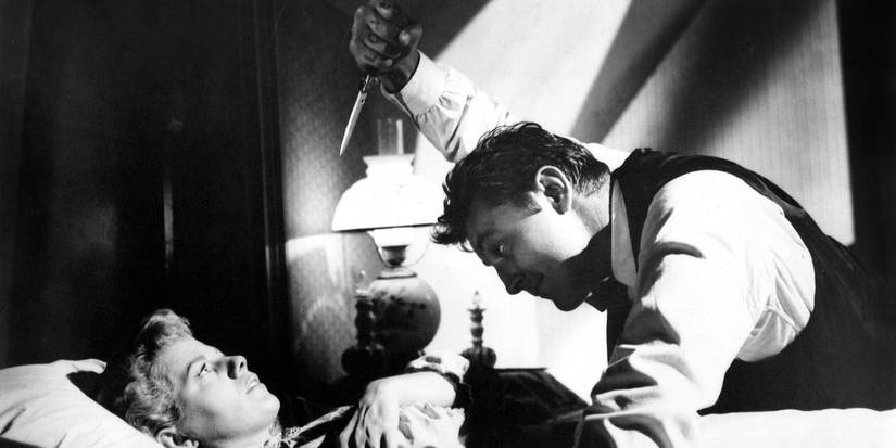 Harry Powell holding a knife above Willa Harper as she lies in bed in The Night of the Hunter