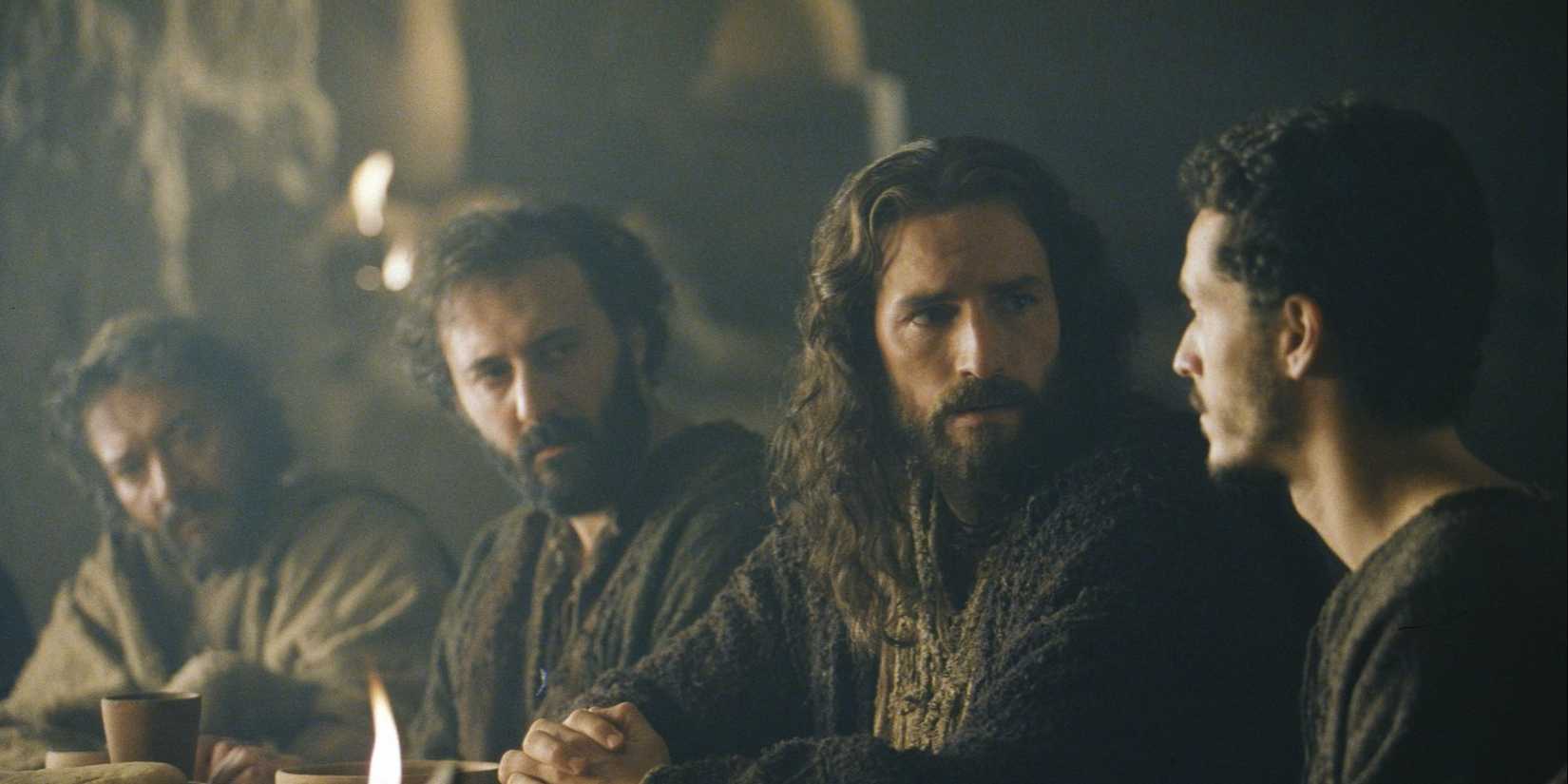 Jim Caviezel as Jesus talks to other people as they sit at a table together in The Passion of the Christ