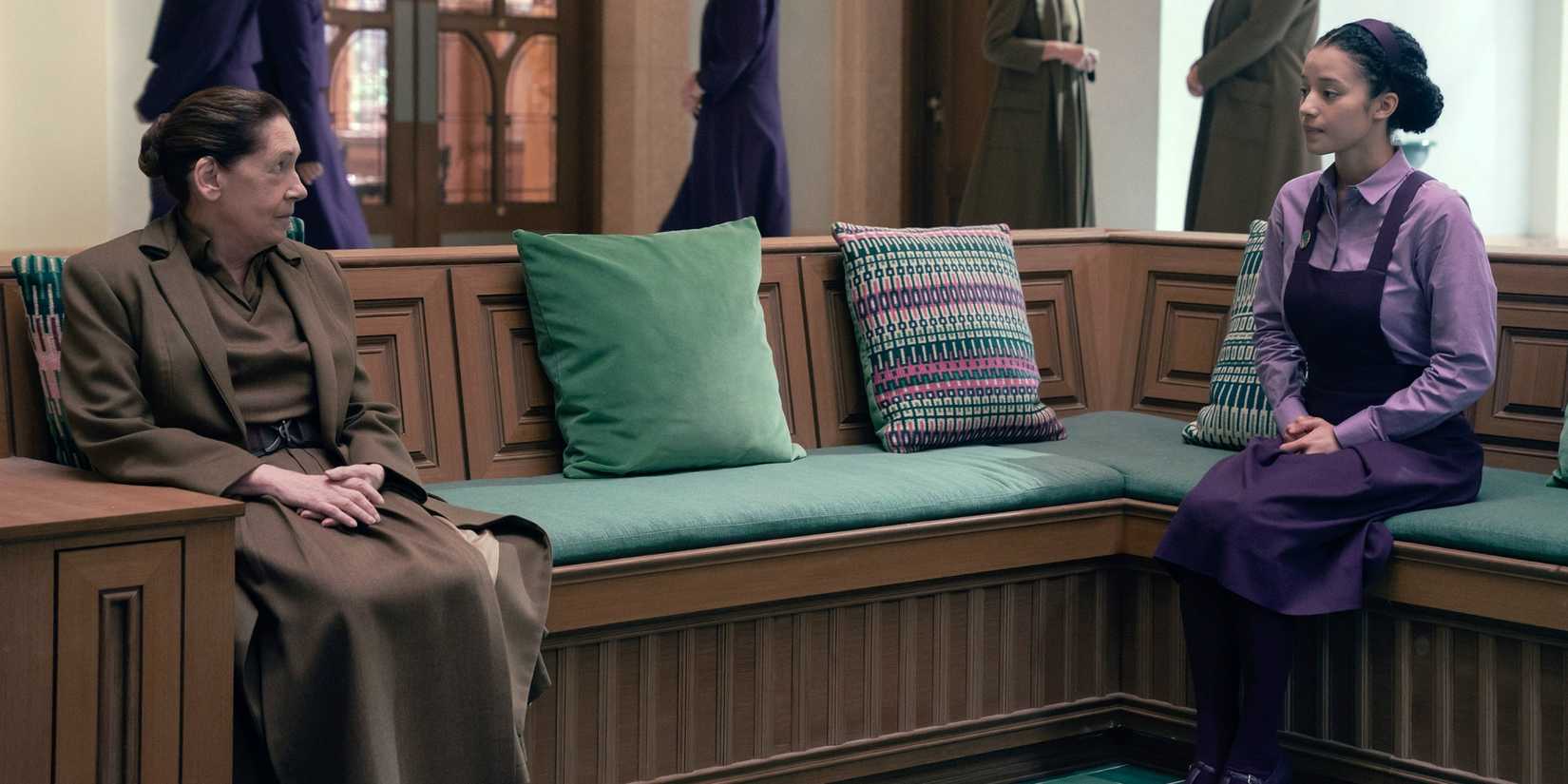 Ann Dowd as Aunt Lydia sitting on a long bench across from Chase Infiniti as Agnes in The Testaments