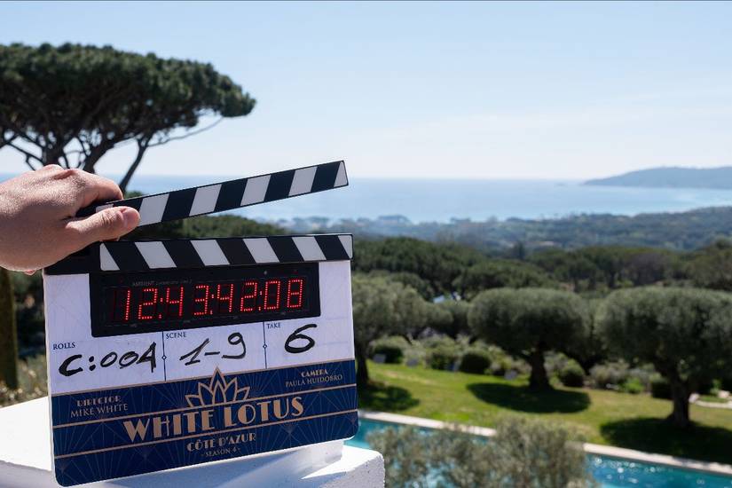 Someone holding a clapper board against a lush landscape signaling the start of filming for The White Lotus Season 4