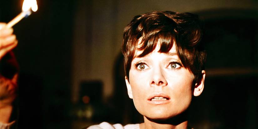 Susy holding up a light match with a fearful expression in Wait Until Dark
