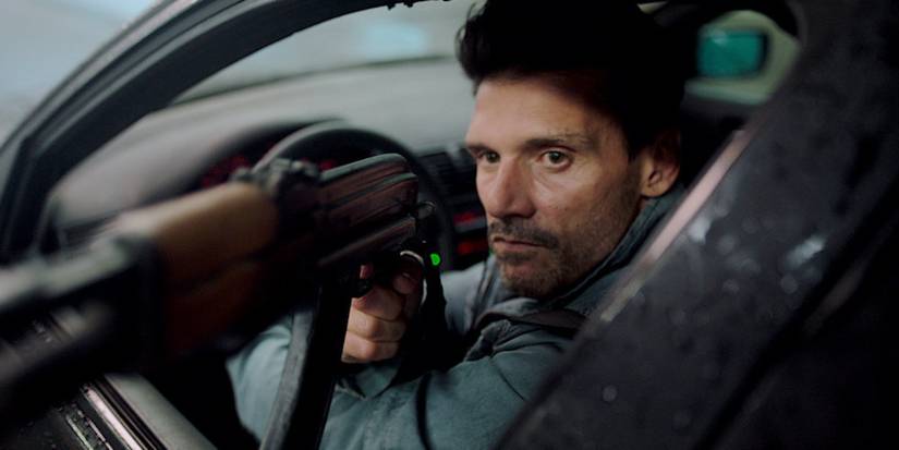 Frank Grillo pointing a gun at someone off screen from his car in Wheelman