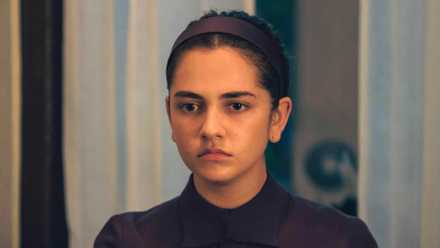 Mattea Conforti as Becka dressed as a Plum and looking serious in The Testaments