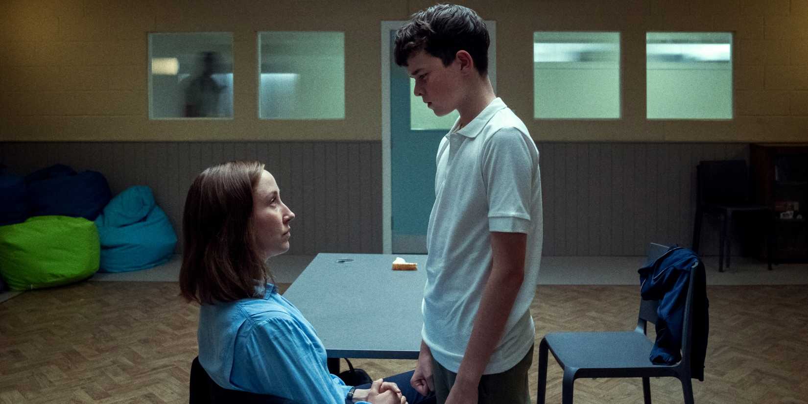 Owen Cooper as Jamie Miller standing over Erin Doherty as Briony Ariston as she sits in Adolescence