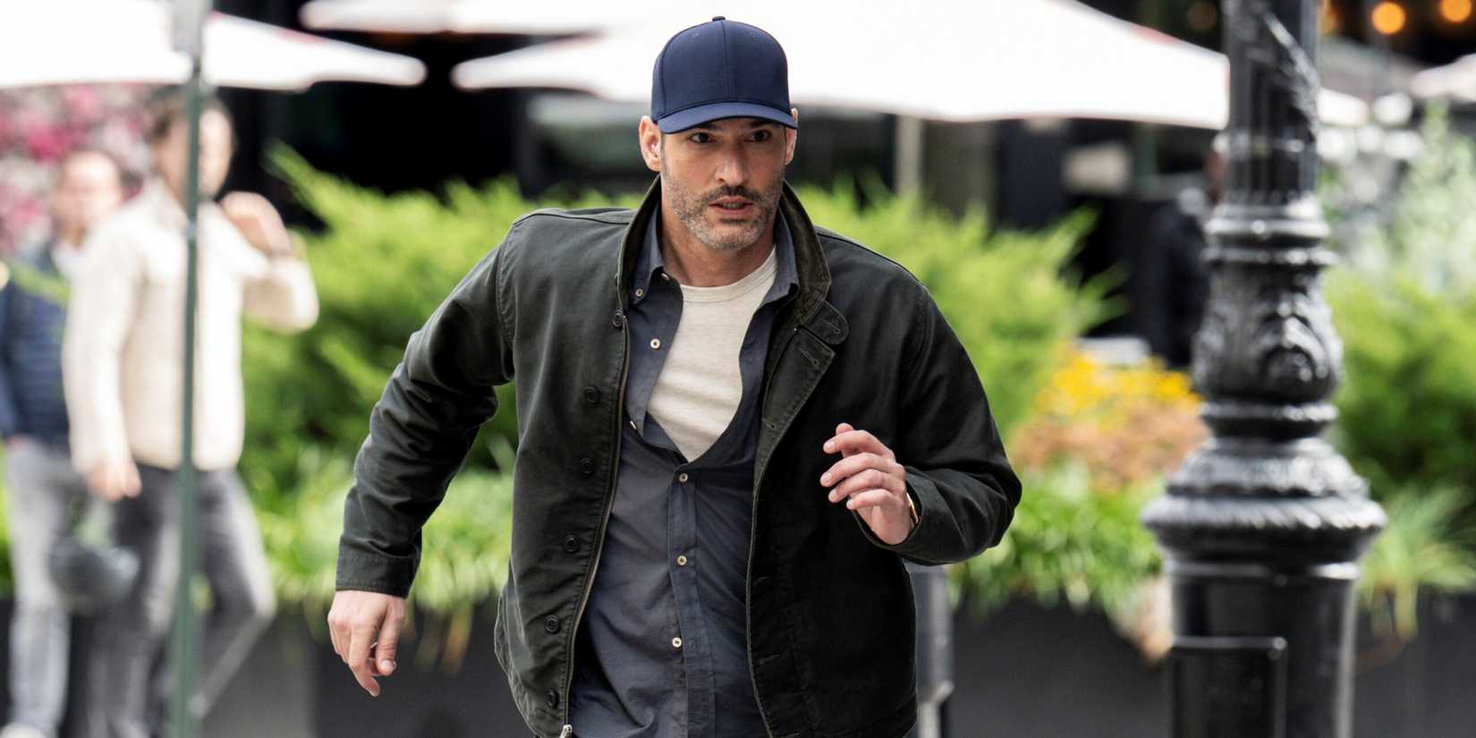 Tom Ellis as CIA Agent Colin Glass running while wearing a baseball cap in the CBS series CIA