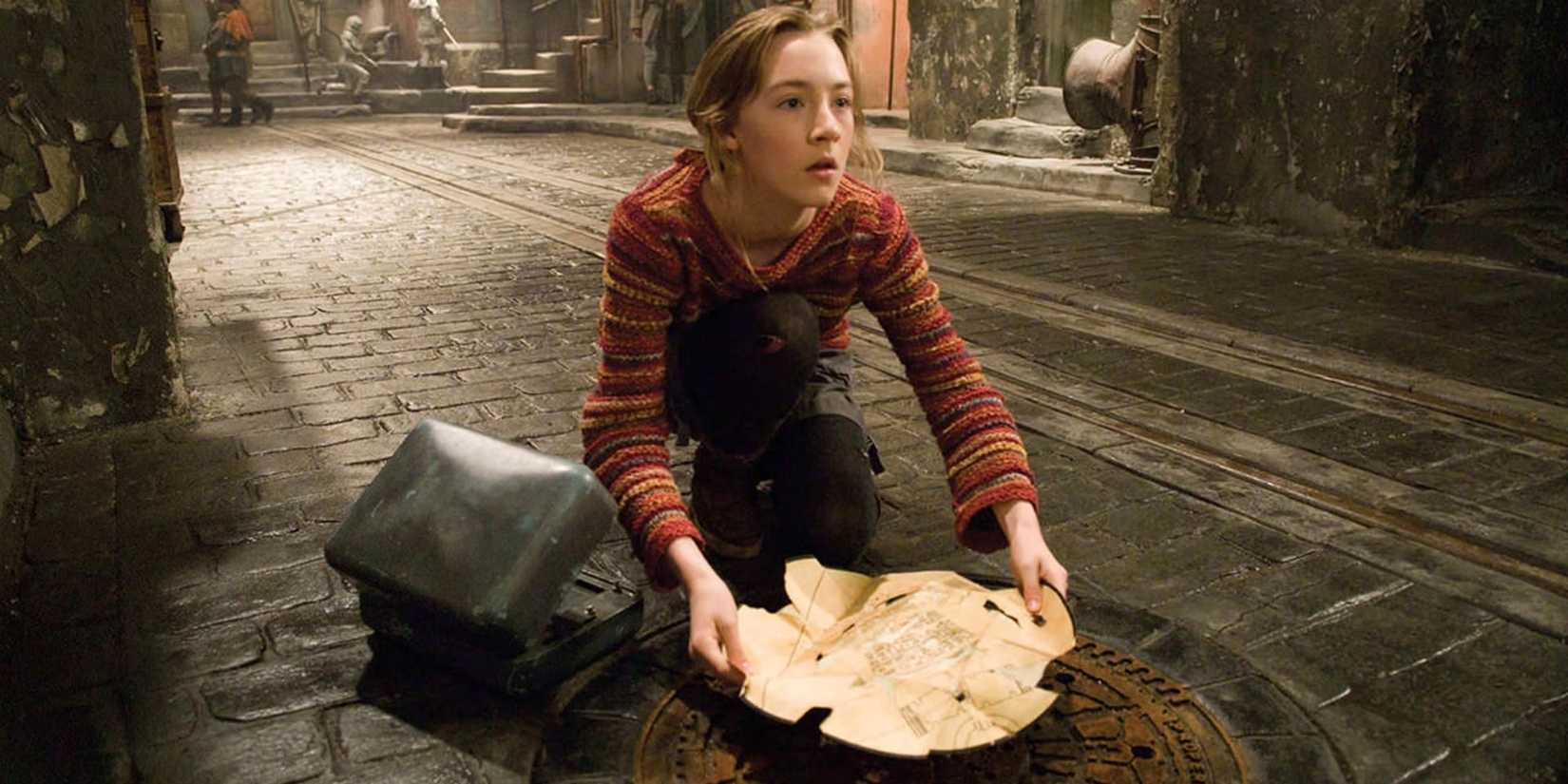Saoirse Ronan as Lina kneeling in the street holding a map in City of Ember.