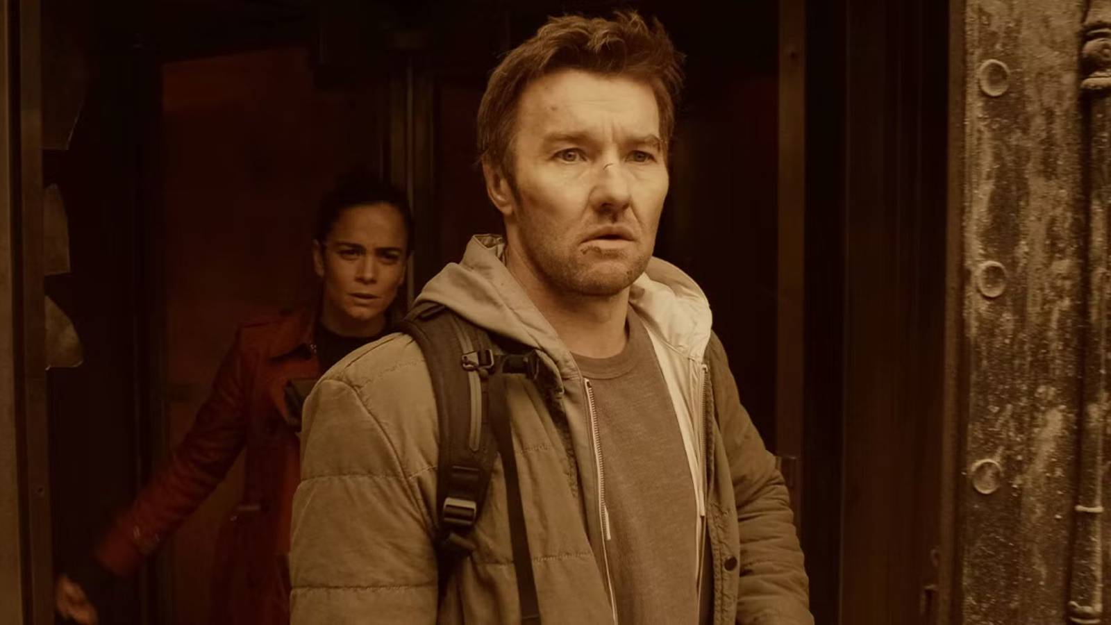 Joel Edgerton and Alice Braga stepping into a lighted area looking alarmed in Dark Matter.