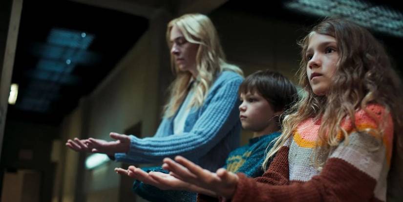 An adult woman and two children holding out their hands in 'Liebes Kind' (Dear Child)