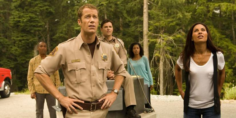The cast of 'Eureka' standing around looking at something.