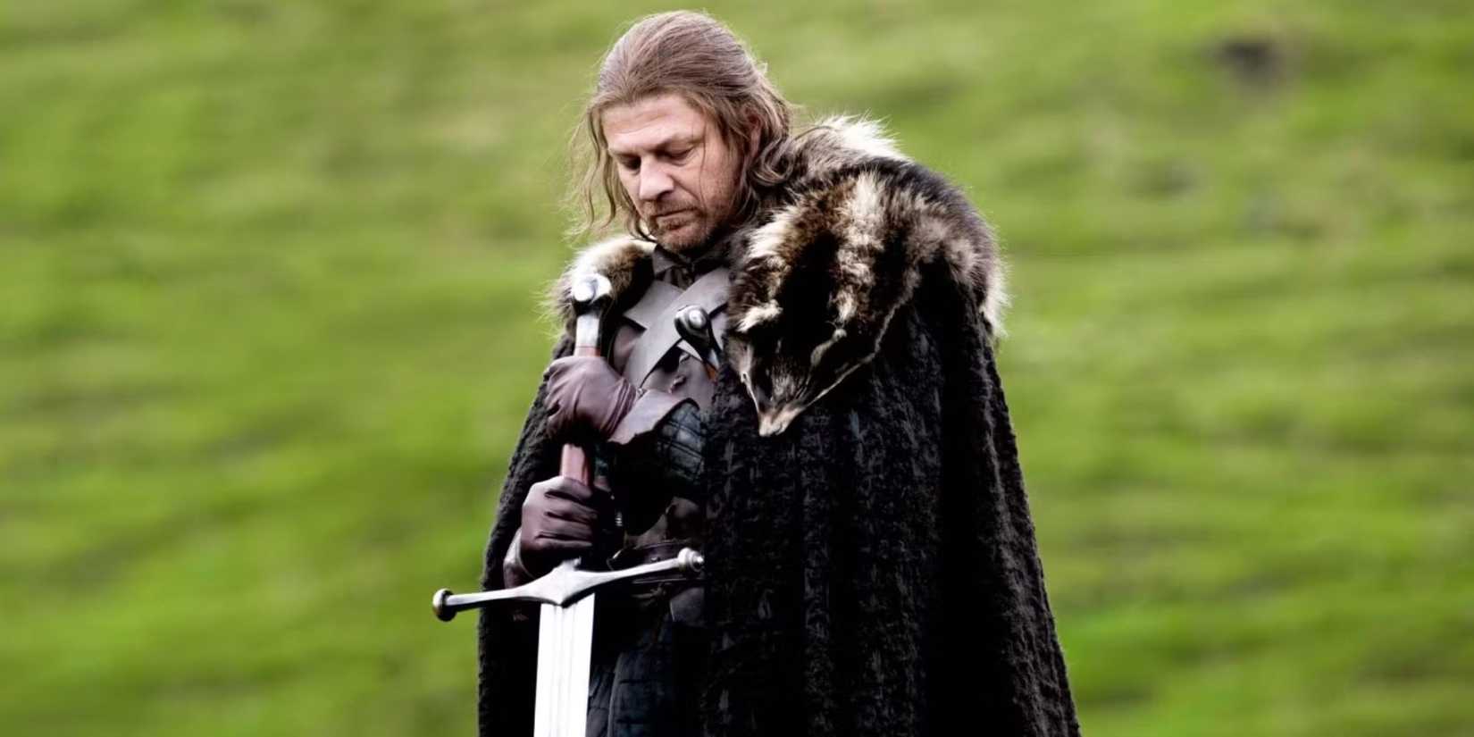 Sean Bean as Ned Stark standing in a green field and holding a sword in Game of Thrones.