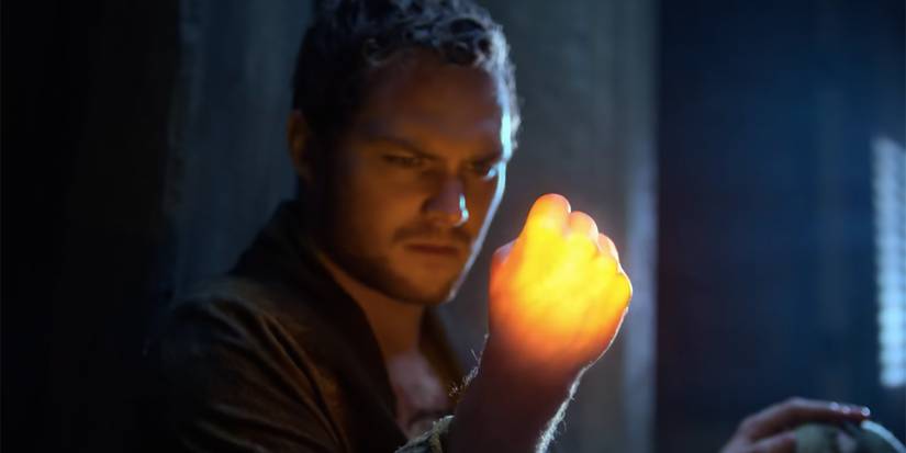 A man holding his hand in a fist while it's glowing in Iron Fist.