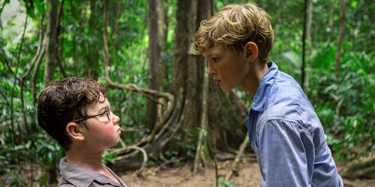 Lox Pratt as Jack standing over to intimidate David McKenna as Piggy in the jungle in Lord of the Flies