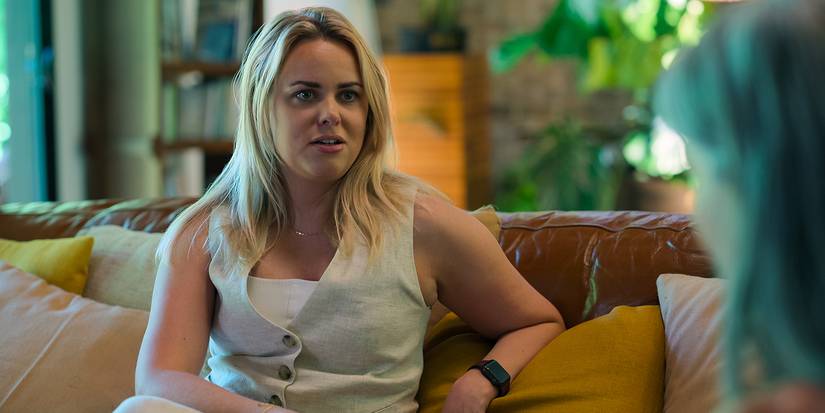 A woman sits on a couch interviewing another in Love Con Revenge.