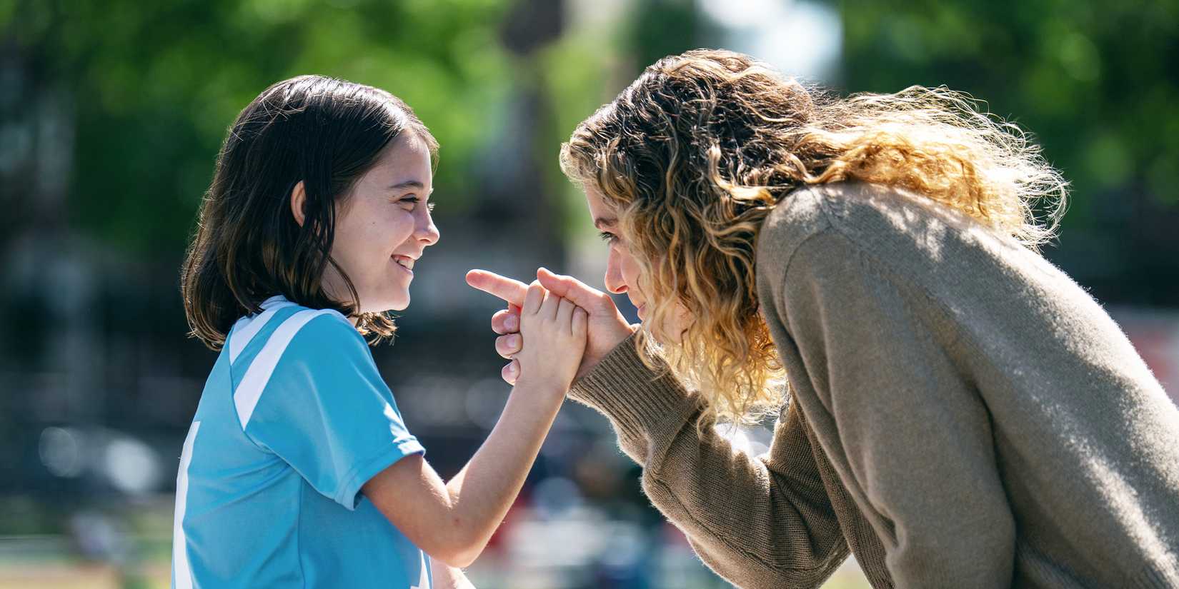Nola Wallace smiling on a soccer field with Tatiana Maslany in Maximum Pleasure Guaranteed