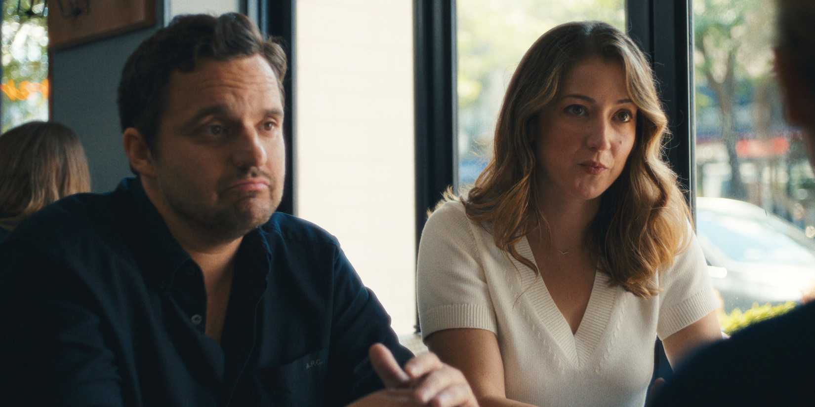 Jake Johnson and Jessy Hodges sitting next to each other and talking to someone at a restaurant in Maximum Pleasure Guaranteed