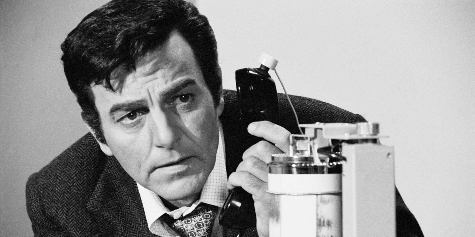 Mike Connors as Mannix holding a phone to his ear and listening in Mannix