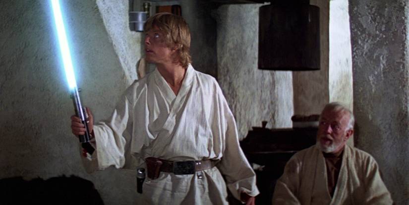 Luke Skywalker holds the Skywalker Lightsaber as Bn Kenobi watches in Star Wars