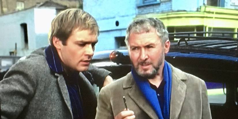 Kaz Garas and Anthony Quayle standing next to a car and talking in Strange Report