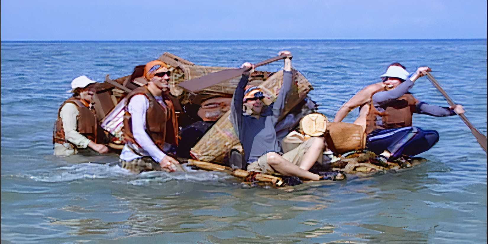 A group of people traversing water with a giant raft filled with supplies in the first episode of 'Survivor'
