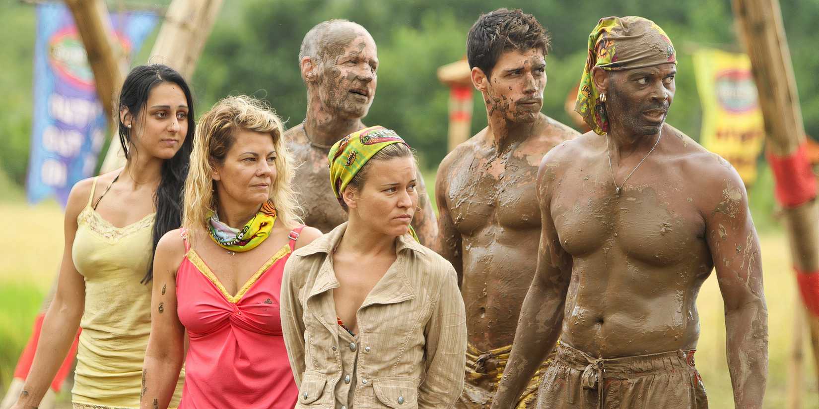 The yellow Tandang tribe looking over while several of their members are covered in mud in 'Survivor: Philippines'