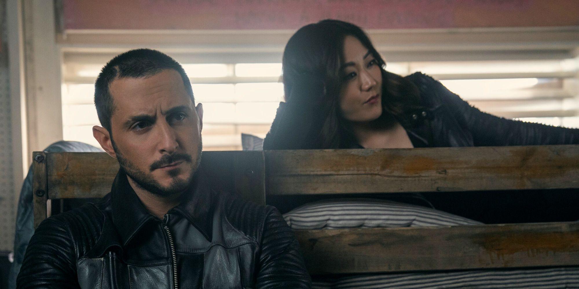 Tomer Capone as Frenchie standing next to Karen Fukuhara as Kimiko laying on a bed in The Boys Season 5