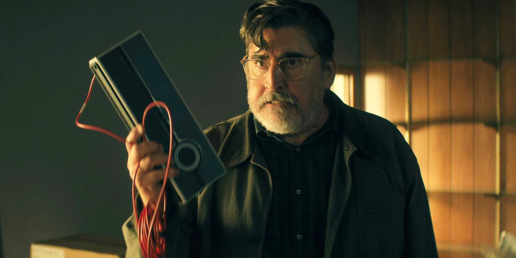 Alfred Molina holding up a piece of equipment and looking angry in The Boroughs