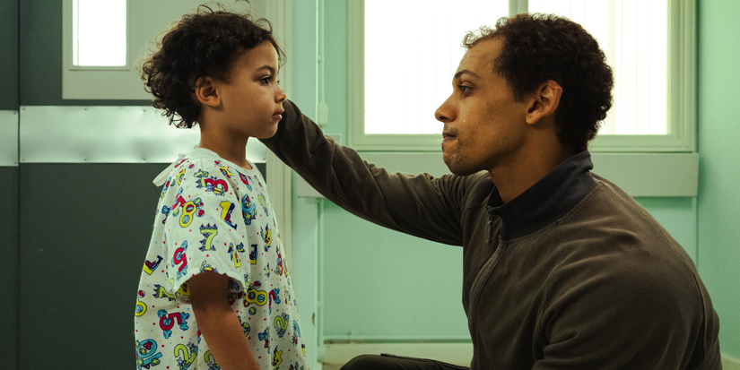 A father cries and strokes his son's head in The Witness