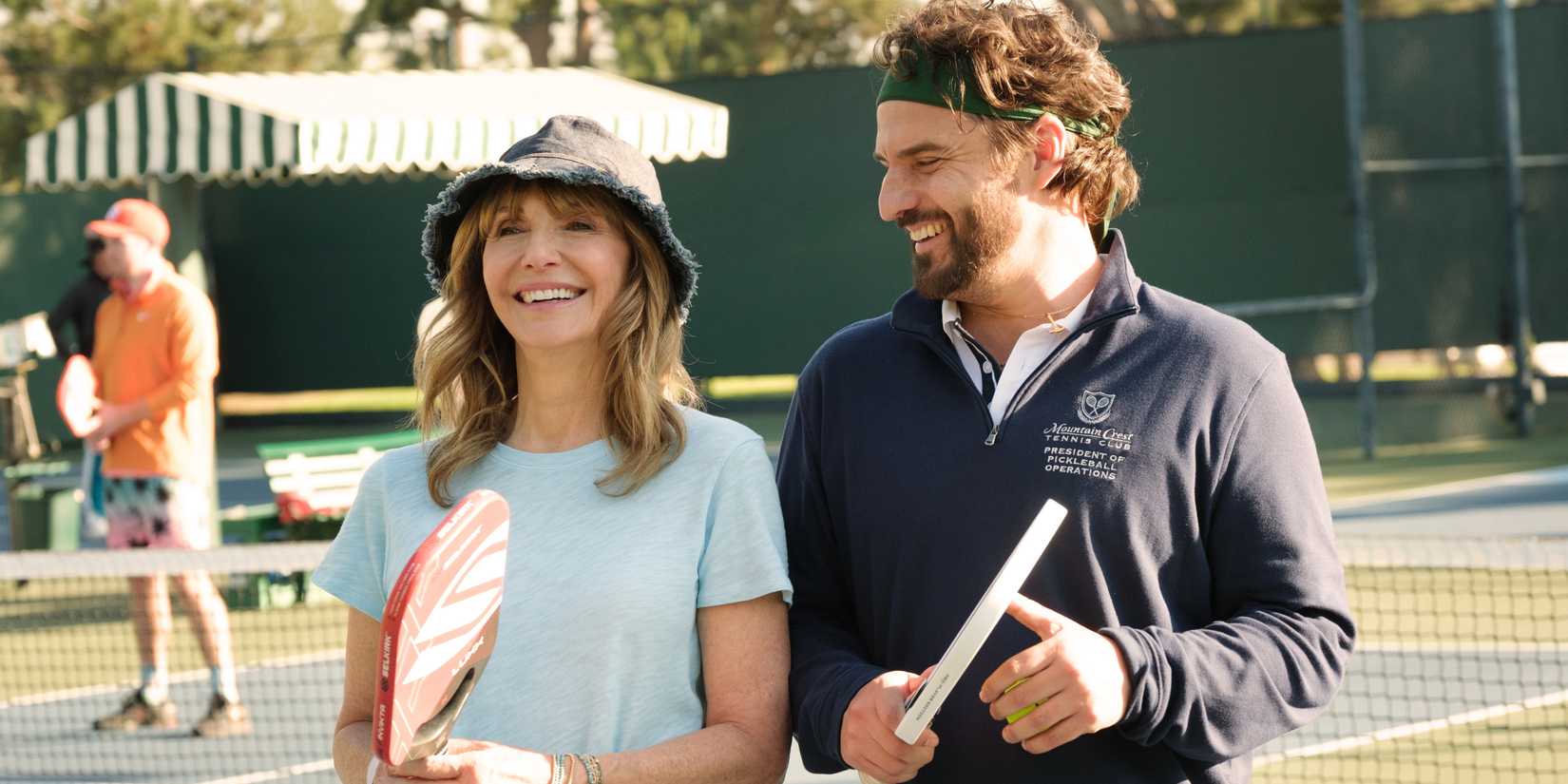 Mary Steenburgen and Jake Johnson laughing together on the pickleball court in The Dink