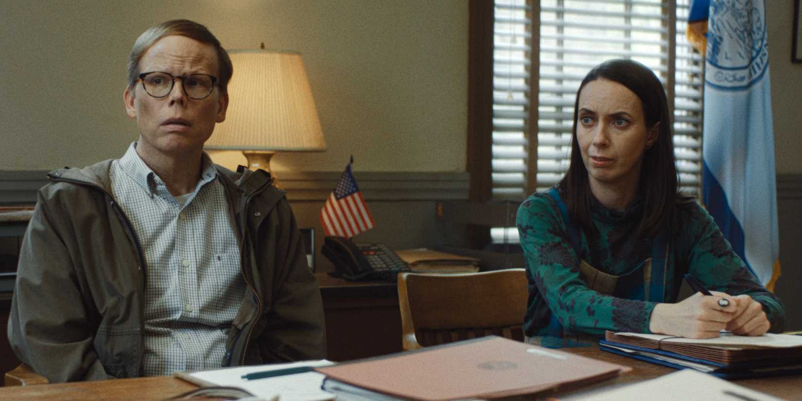 Kate O'Flynn as Patricia sitting at a table next to Jeff Hiller as Dale in Widow's Bay