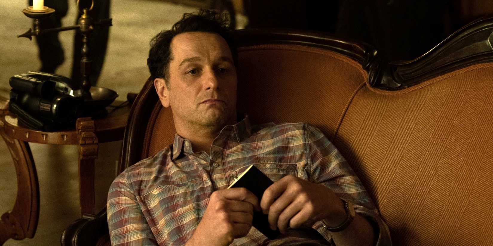 Matthew Rhys as Tom laying down on a couch in Widow's Bay