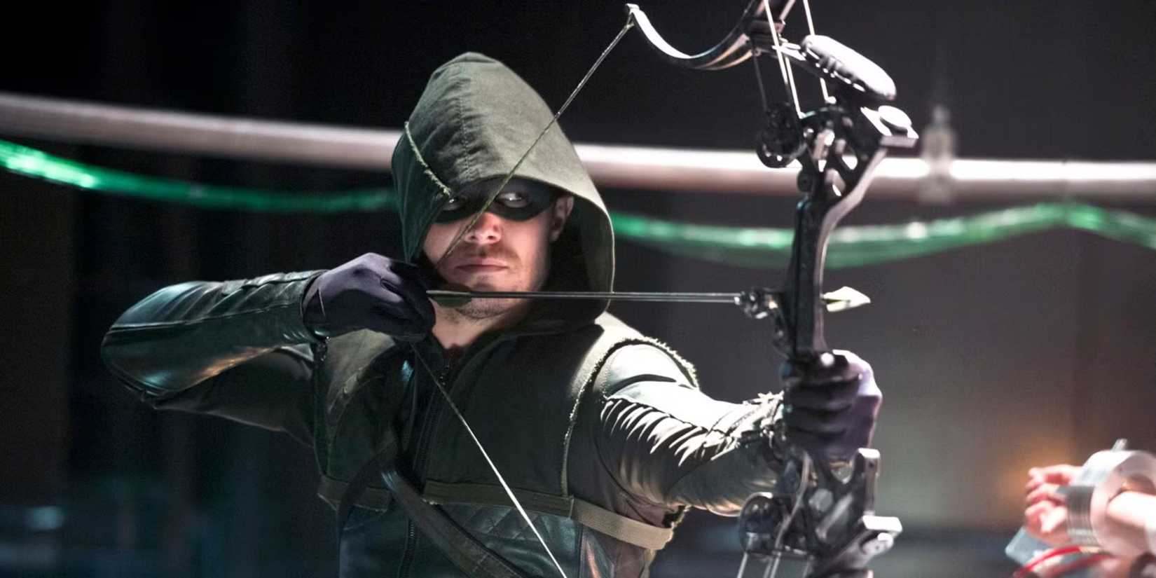 Stephen Amell as the Arrow aiming his arrow at someone off-camera in Arrow