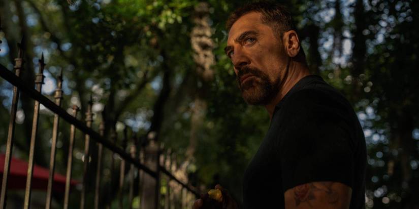 Max Cady (Javier Bardem) holding an apple in front of a wrought iron fence in 'Cape Fear'