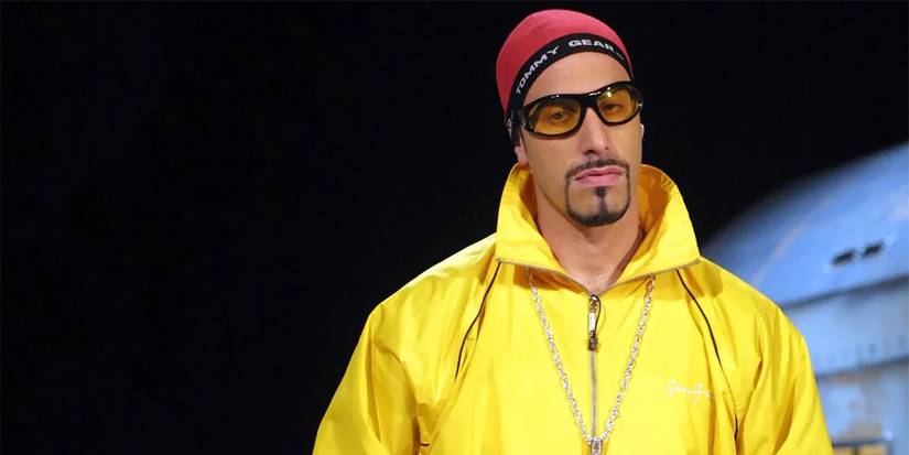 Ali G posing with a red cap and yellow jacket in Da Ali G Show.