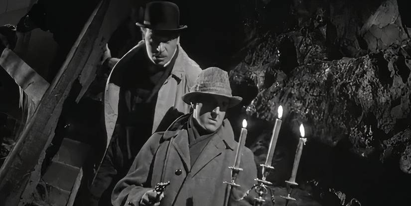 Basil Rathbone, as Sherlock Holmes, walks with a pistol and candelabra in The House of Fear